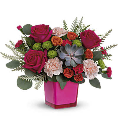 Low arrangement of hot pink roses, peach carnations, green mums and a succulent in a bright pink cube vase