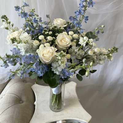 Blue and white bouquet with roses in a clear glass vase