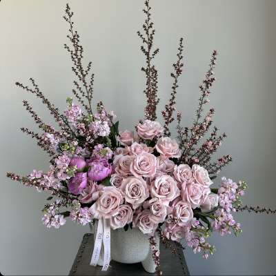Pink roses and lilac flowers arranged in a gray vase