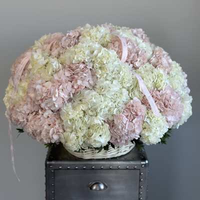 Large pastel hydrangea arrangement in a white basket