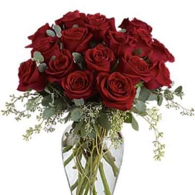 Arrangement of long-stemmed red roses with filler in a clear glass vase