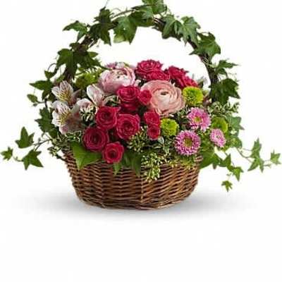 Basket of pink and red flowers with white accents and an arching ivy-covered handle