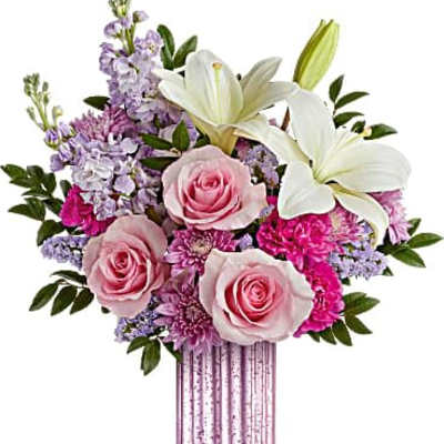 Pink and white bouquet with roses, lilies, and mixed flowers in a tall pink glass vase