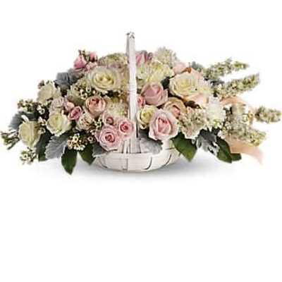 Low pastel arrangement of pink and ivory roses in a white handled basket