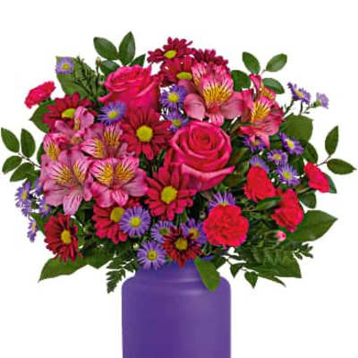 Bright bouquet of pink roses, alstroemeria, and purple daisies in a matte purple vase