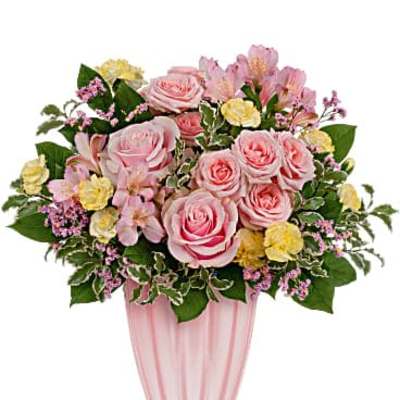 Pink roses with yellow carnations and pink alstroemeria in a pink striped glass vase