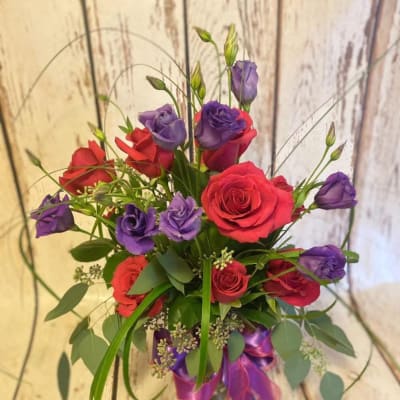 Bouquet of red roses and purple lisianthus in a glass vase
