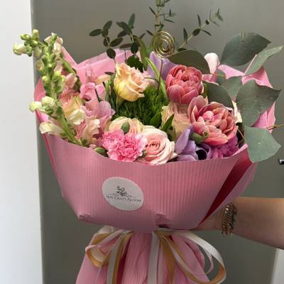 Pink mixed bouquet with roses and purple blooms wrapped in pink paper