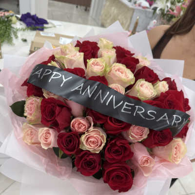 Bouquet of red and blush roses with a black anniversary ribbon