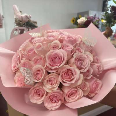 Bouquet of pink roses wrapped in pink paper with butterfly picks