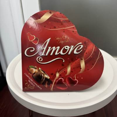 Heart-shaped box of assorted chocolates on a white table