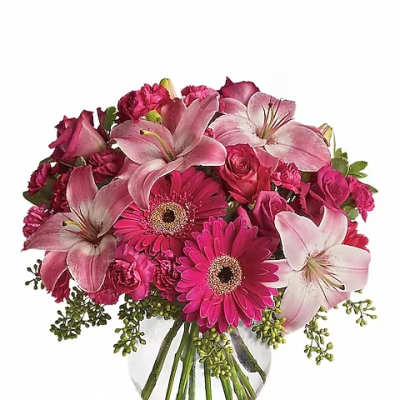 Pink lilies, roses, and gerbera daisies in a clear glass vase