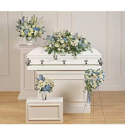White casket surrounded by blue and white floral arrangements