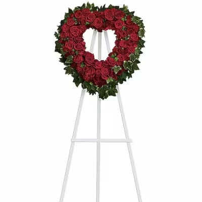 Heart-shaped red rose wreath on a white easel