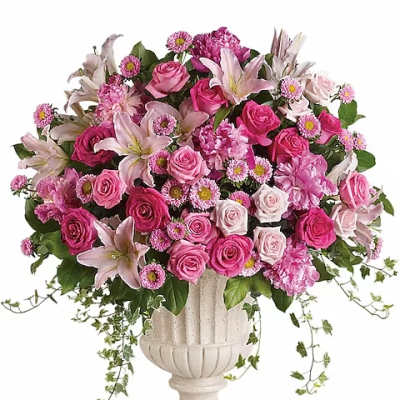 Pink roses and lilies arranged in a white urn vase
