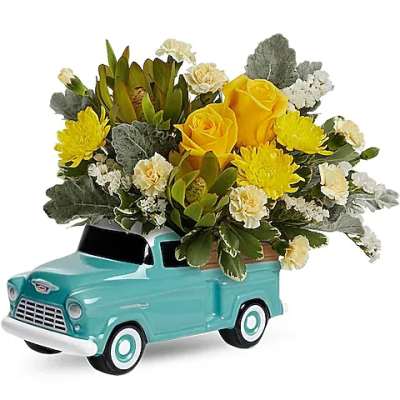 Yellow roses and chrysanthemums arranged in a turquoise truck planter