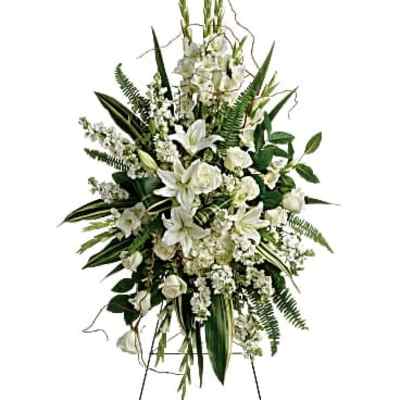 White floral standing spray on an easel with lilies and roses