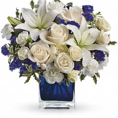 White lilies and roses arranged in a blue glass vase