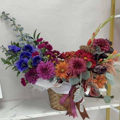 Colorful mixed flower arrangement in a woven basket with ribbon