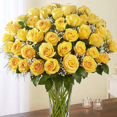 Yellow roses arranged in a clear glass vase with baby's breath