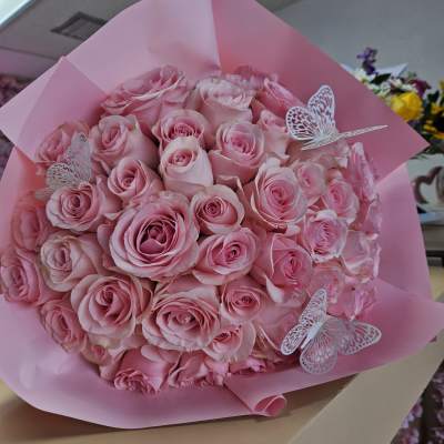 Bouquet of pink roses wrapped in pink paper with butterfly decorations