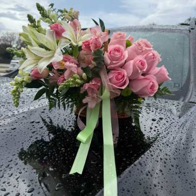 Pink rose and lily bouquet with ribbon on a car hood
