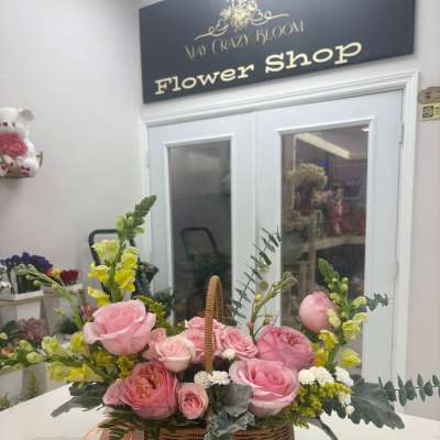 Pink roses and yellow snapdragons in a wicker basket with ribbon