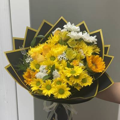 Bouquet of yellow and white daisies wrapped in black paper with gold trim