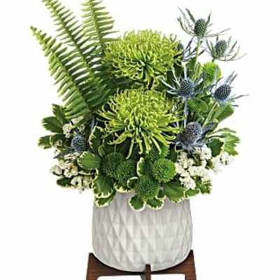 Green floral arrangement in a white textured pot on a wooden stand