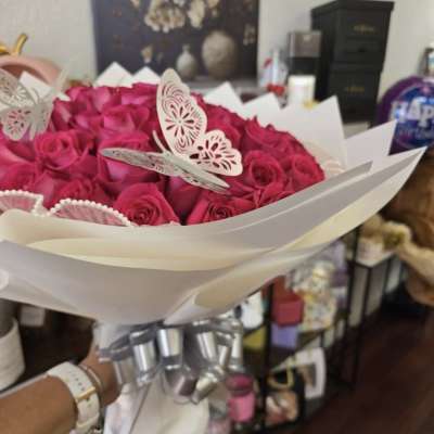Bouquet of bright pink roses wrapped in white paper with butterfly decorations