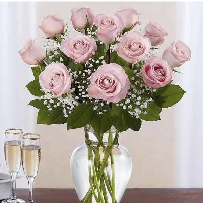 Pink roses arranged in a clear glass vase with baby's breath