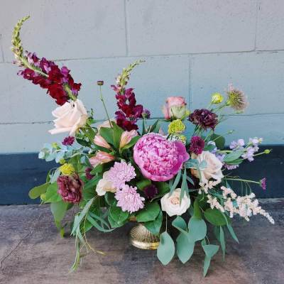 Mixed floral arrangement with pink peonies and roses in a low vase