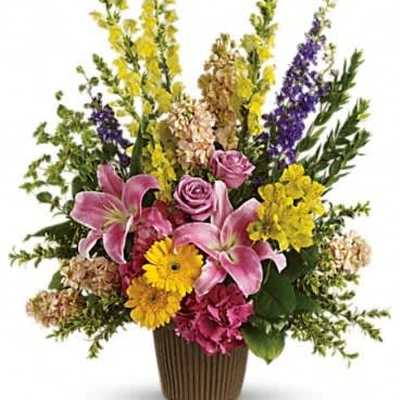 Tall mixed arrangement with pink lilies, roses, yellow gerberas, and snapdragons in a brown vase