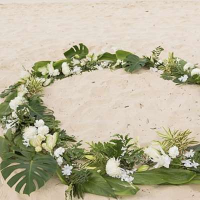 White floral wreath with tropical leaves arranged in a circle