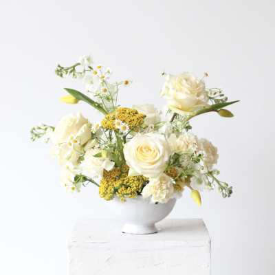 White and yellow floral arrangement in a white bowl vase