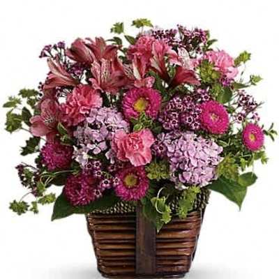 Pink and purple mixed flower basket arrangement in a brown woven container