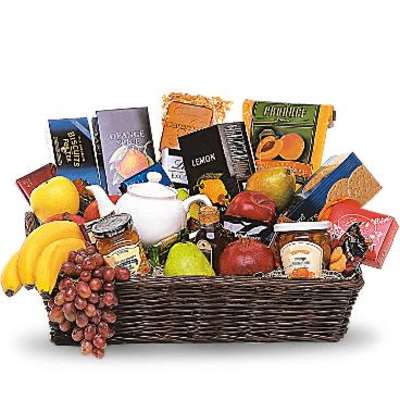 Large gourmet gift basket with assorted fruits, snacks, and a white teapot