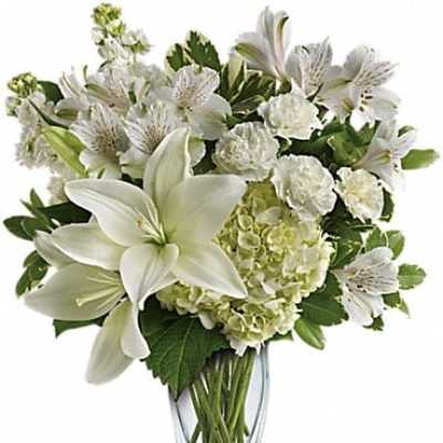 White lilies and hydrangeas arranged in a clear glass vase