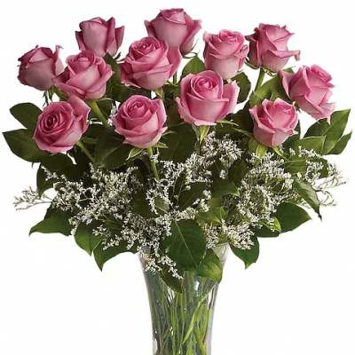 Pink roses arranged in a clear glass vase with white filler flowers