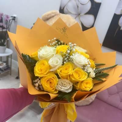 Bouquet of yellow and white roses wrapped in orange paper