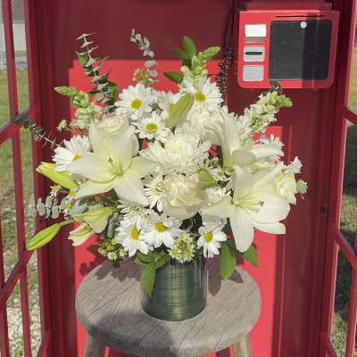 White lilies and daisies arranged in a green vase