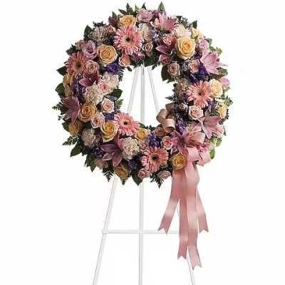 Floral wreath on a white stand with pink ribbon
