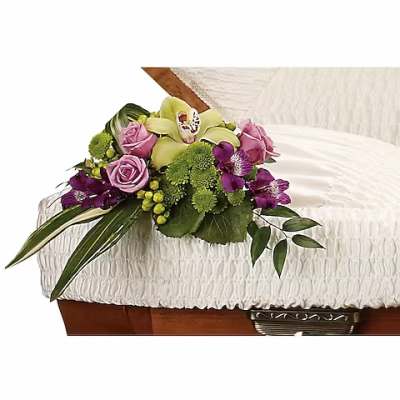 Pink and purple floral spray on a white casket
