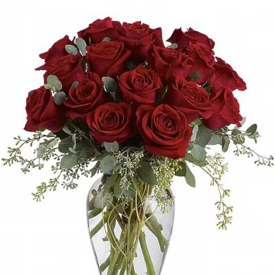 Red roses arranged in a clear glass vase with airy greenery