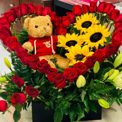 Heart-shaped rose arrangement with a teddy bear and sunflowers in a black box