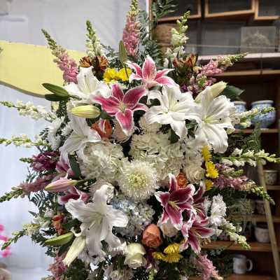 Large standing floral spray with white and pink lilies, hydrangeas, and mixed blooms