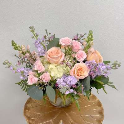 Pastel bouquet of roses, hydrangea, and lavender flowers in a glass vase