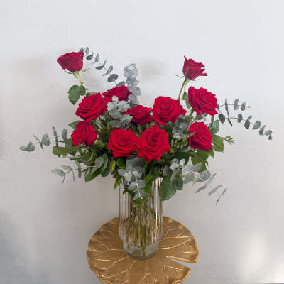 Red roses in a clear glass vase with silver eucalyptus