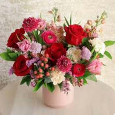 Bouquet of red and pink flowers in a pale pink vase