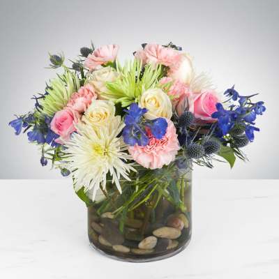 Mixed bouquet of pink and cream flowers in a glass vase with stones